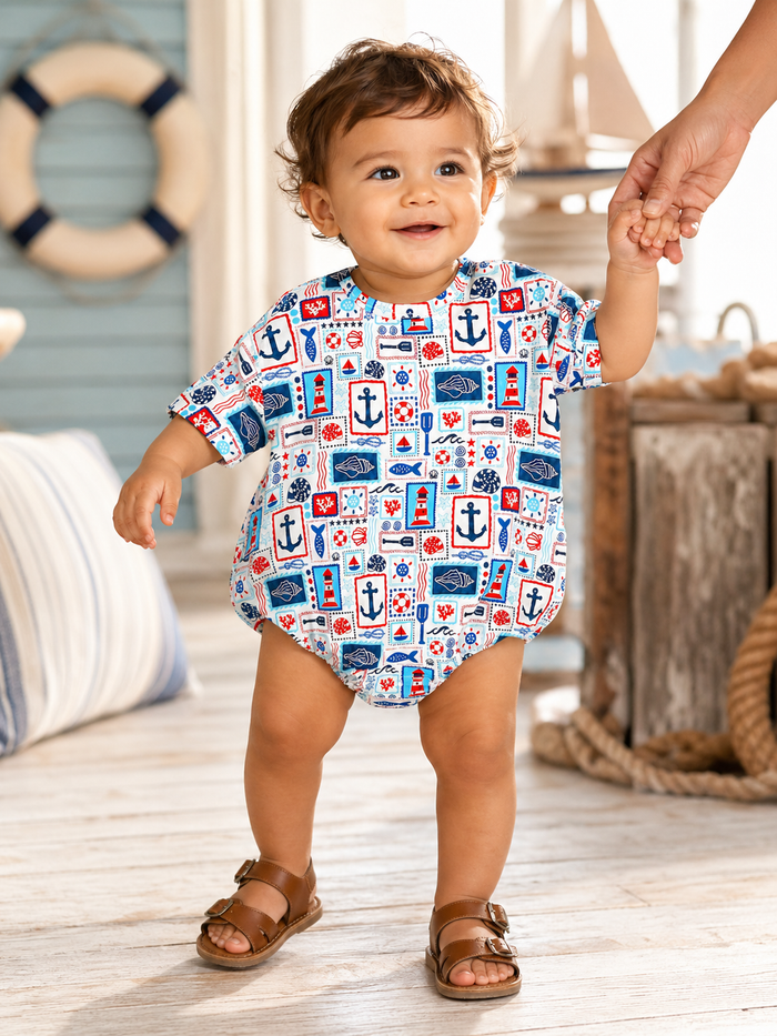 Smiling toddler in a nautical-patterned outfit walking while holding an adult's hand on a beach-inspired interior.
