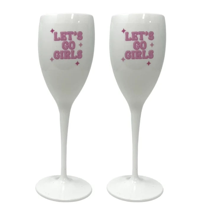 Two individuals holding clear plastic champagne glasses, wearing pink outfits, with one holding a phone and both smiling.