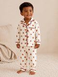 Smiling child in floral pajamas stands on a soft rug, exuding warmth and joy.