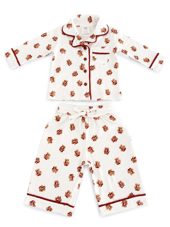 Kids' white pajama set with bear prints, featuring a button-up top and drawstring pants with red accents.