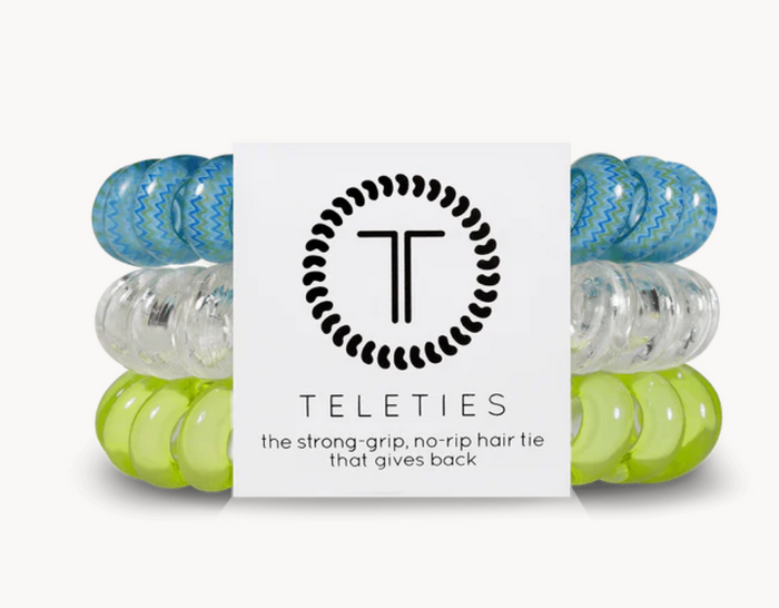A pack of three Teleties hair ties with a logo, colors green, clear and blue pattern.
