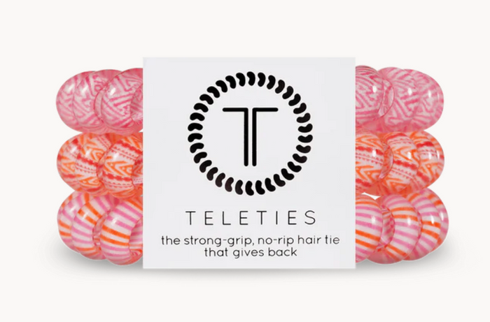 A pack of three Teleties hair ties with a logo, colors pink and orange patterned.