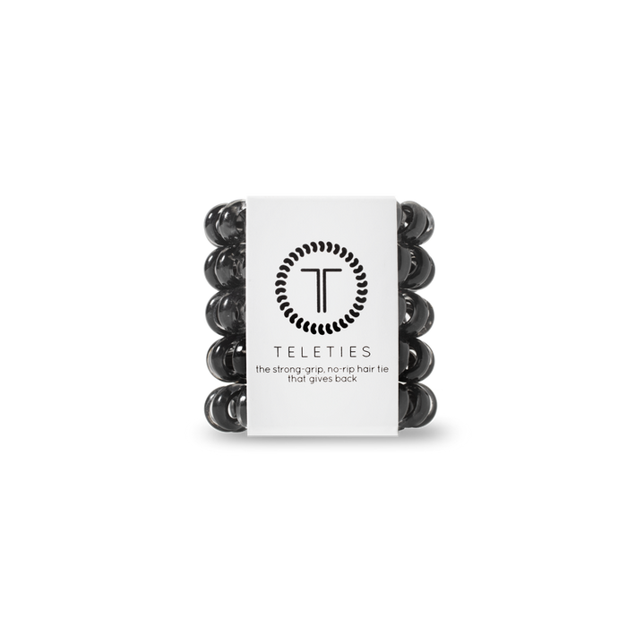 Stack of black hair ties with a white label featuring 'Teleties' branding on a white background.