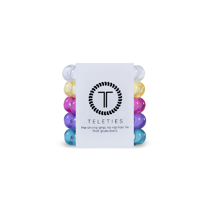 Stack of white, yellow, pink, purple, and blue hair ties with a white label featuring 'Teleties' branding on a white background.