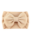 Beige headband with a large textured bow, perfect for adding style to any outfit.