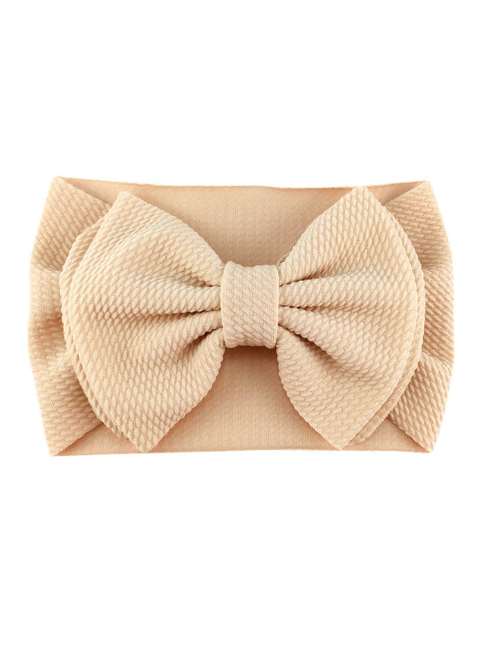 Beige headband with a large textured bow, perfect for adding style to any outfit.