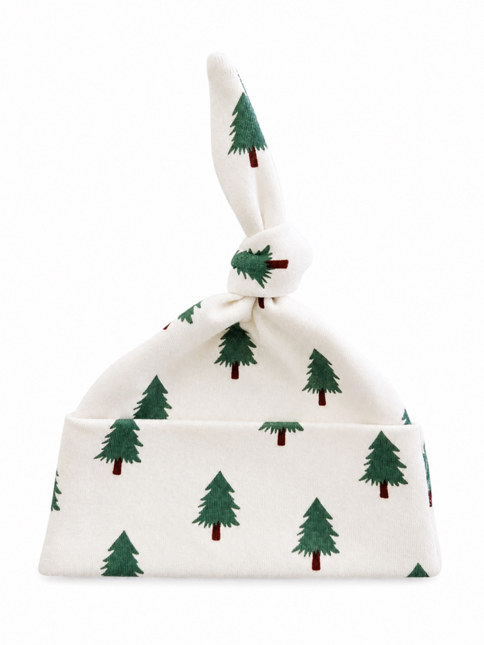 White baby hat with green tree patterns and a knotted top. Ideal for winter and festive occasions.