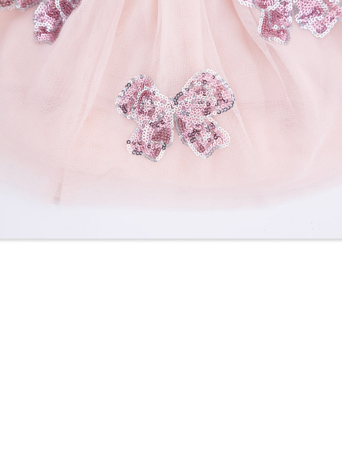 Pink tulle fabric adorned with shiny sequined bows. Elegant and playful design for children's wear.