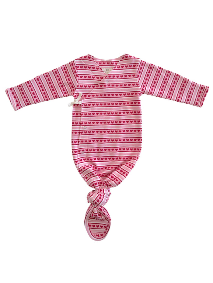 Baby sleep sack in pink with heart patterns, featuring long sleeves and a knotted bottom for easy diaper changes.