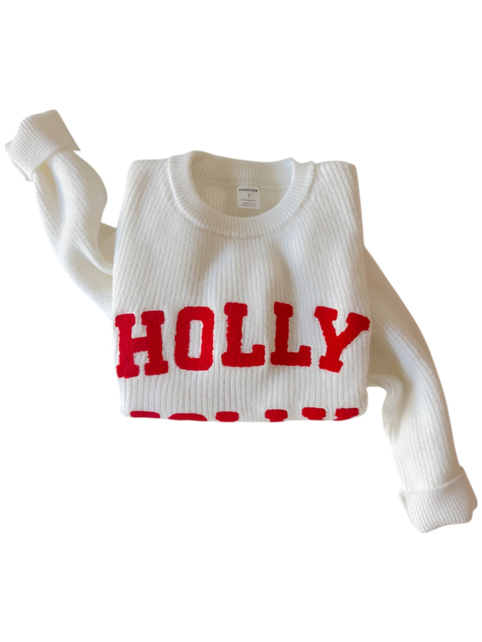 White sweater with red "HOLLY" lettering, styled with a ribbed texture and rolled sleeves.
