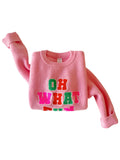 Pink sweater featuring colorful lettering that reads "OH WHAT FUN."