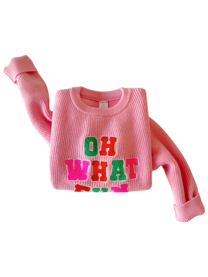 Pink sweater featuring colorful lettering that reads "OH WHAT FUN."