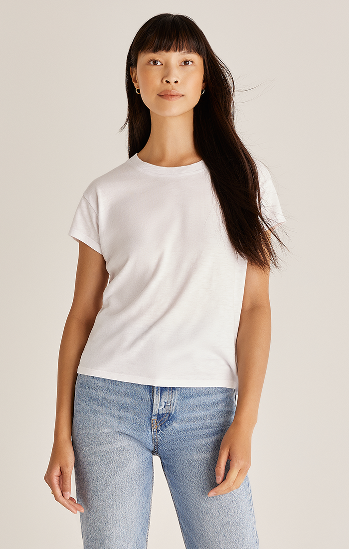 A woman wearing a beige 'Modern Slub Tee' with short sleeves and a round neckline, paired with blue jeans.